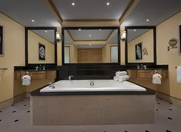 Spacious villa bathroom with large tub, mirrors, and white bath towels