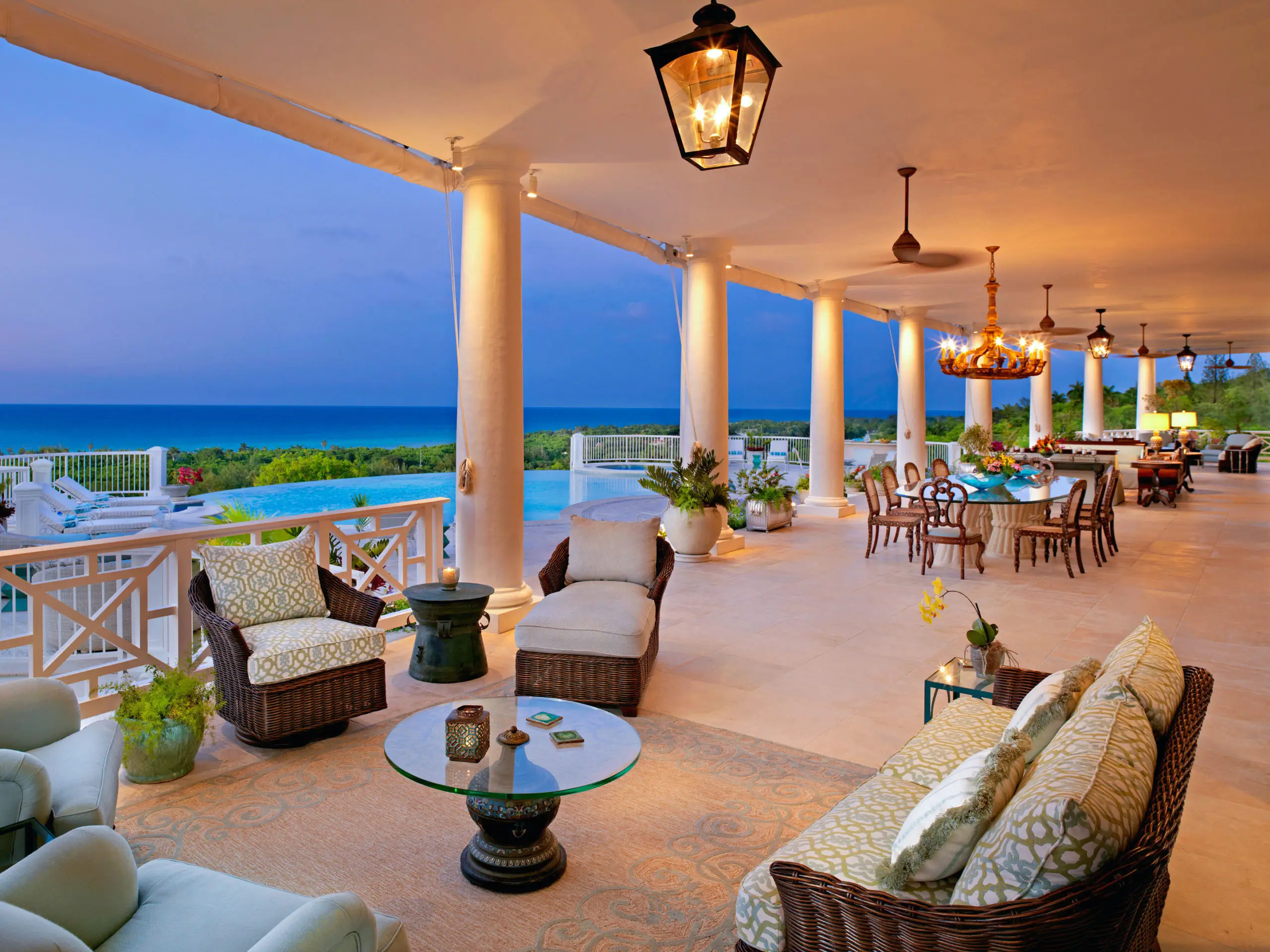 Stylish open-air patio with tables and chairs next to pool and ocean