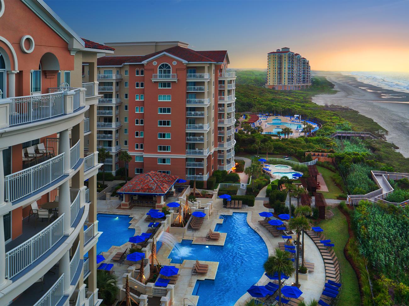 Aerial of exterior of Oceanwatch timeshare showing pool, dunes and beach views