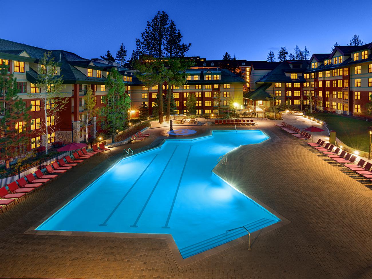Illuminated outdoor pool and exterior of Marriott's Timber Lodge resort timeshare at dusk